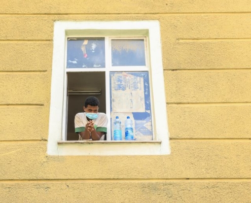 A man wearing a mask standing at a window