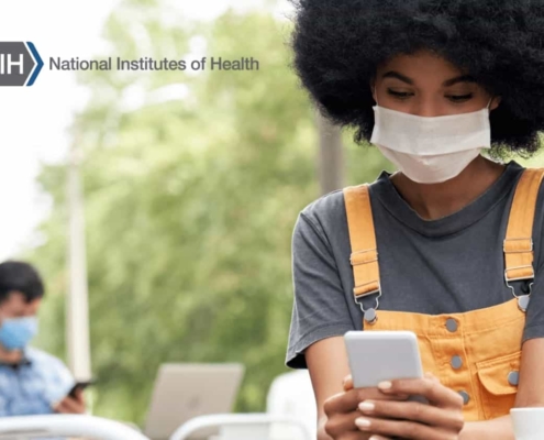A woman using her smartphone while wearing a face mask.