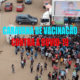 A group of people in Mozambique gathered around a stage that's on the back of a truck. The text reads: "Caravana de vacinacão contra a COVID-19"
