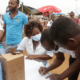 A healthcare worker in Mozambique helping community members sign up to receive the COVID-19 vaccine